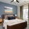 Model bedroom at our apartments for rent in Peachtree Corners, featuring a queen bed and windows with blinds.